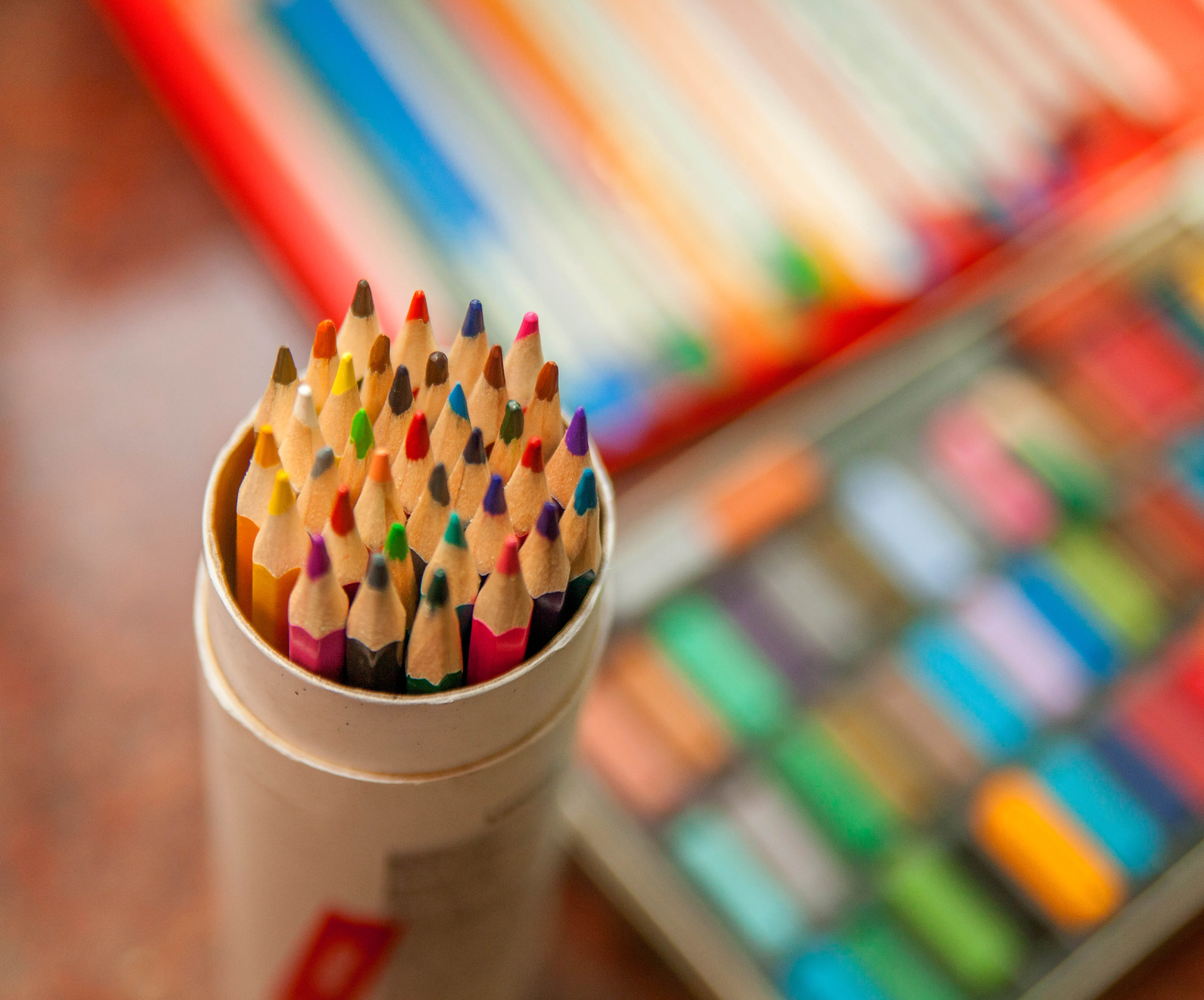 pencils in cylinder container with paints in the background