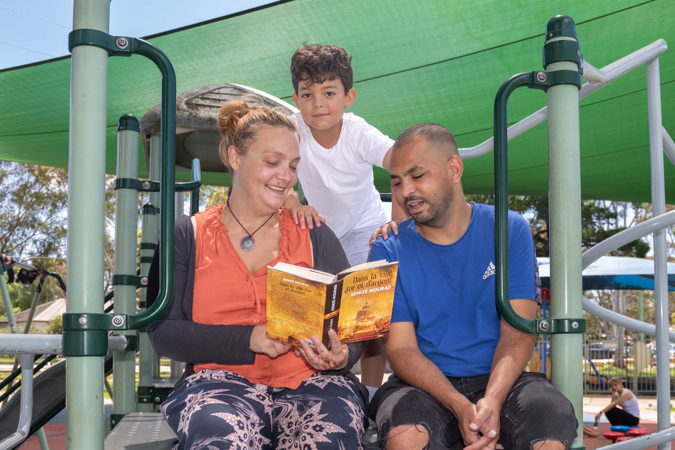 Culturally diverse family reads French book at park