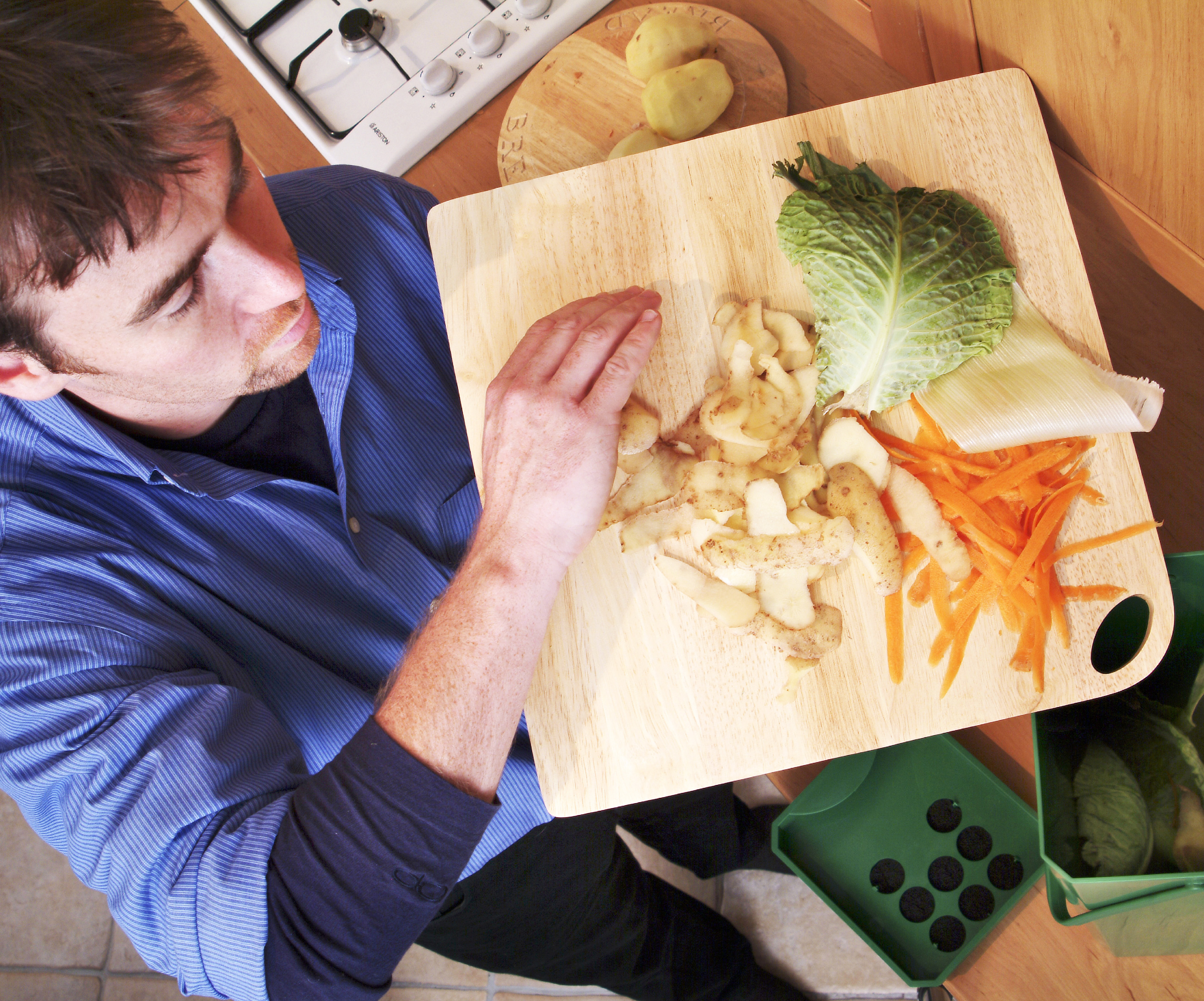overhead shot of a man with vegetable scraps using bokashi bin