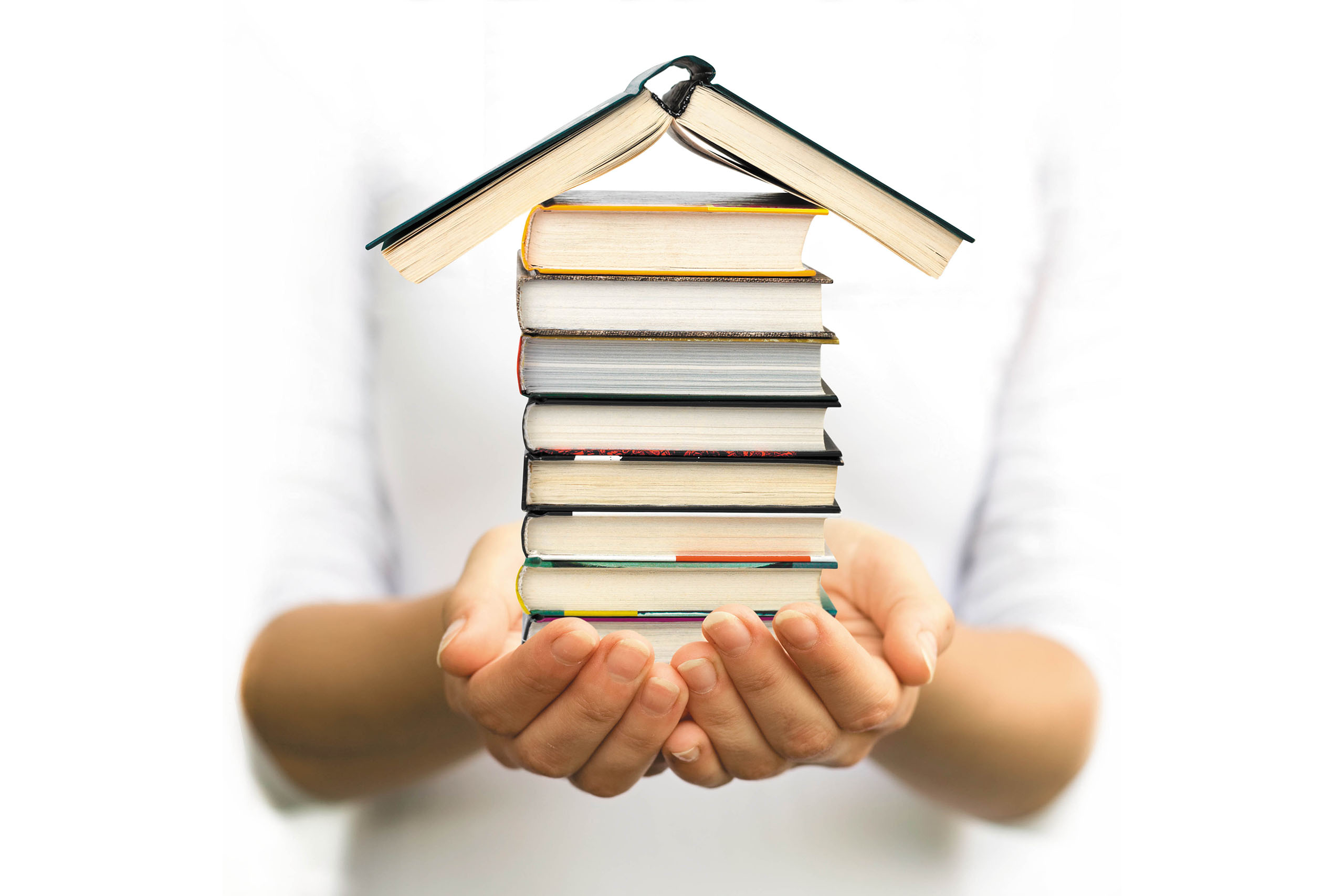 person holding a stack of books in the shape of a house