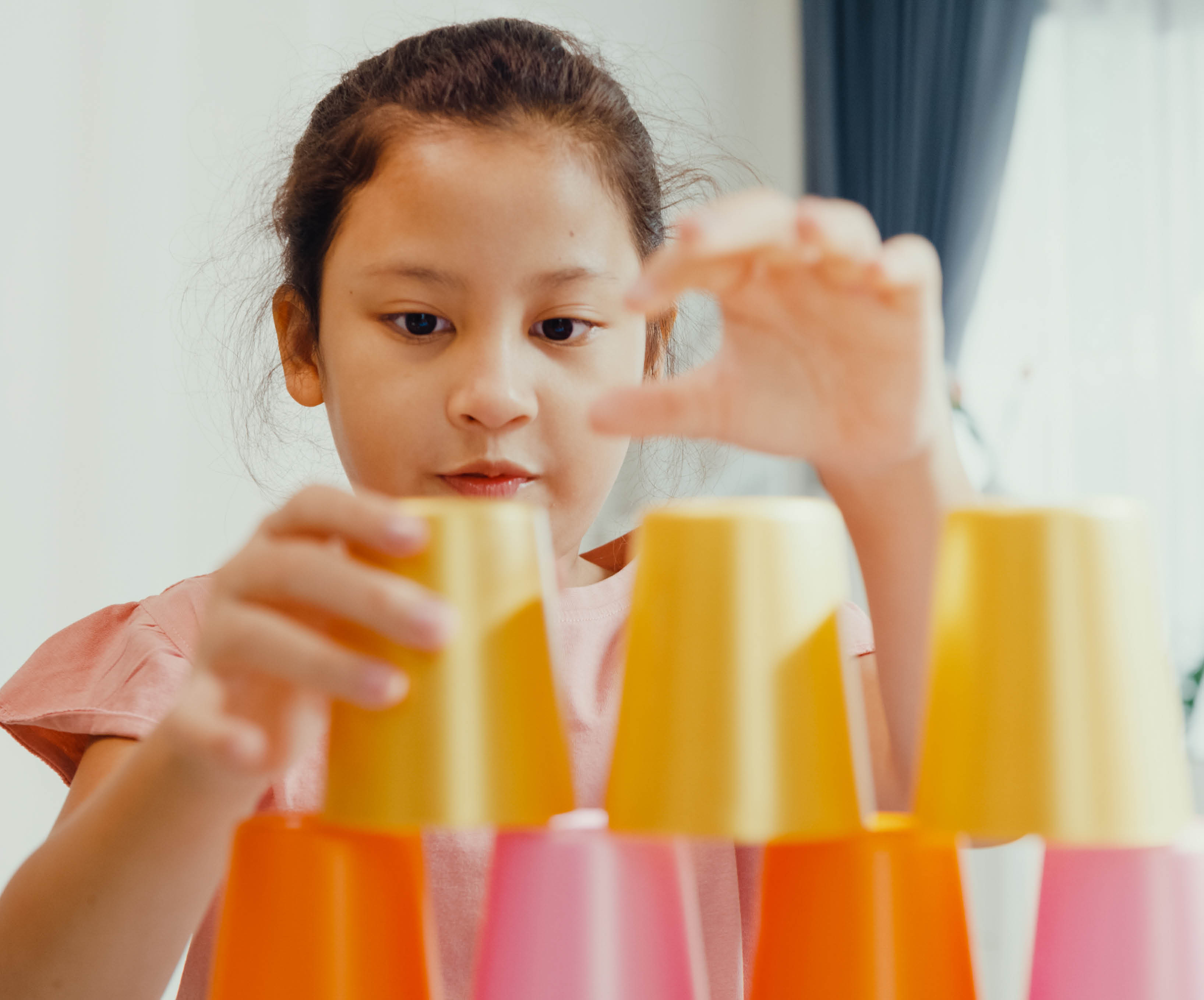 Young girl playing cup stacking game