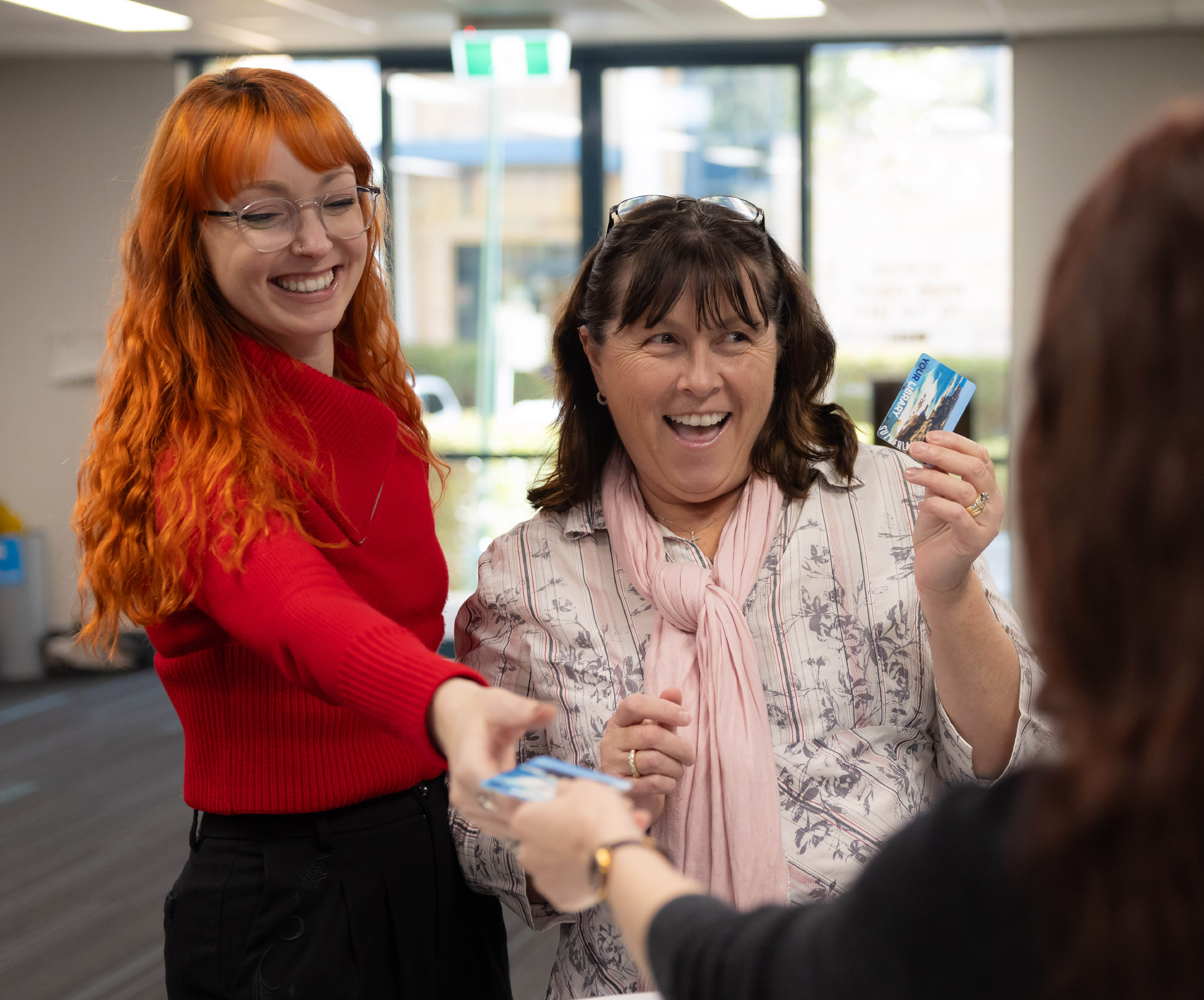 Two women smile while joining the library