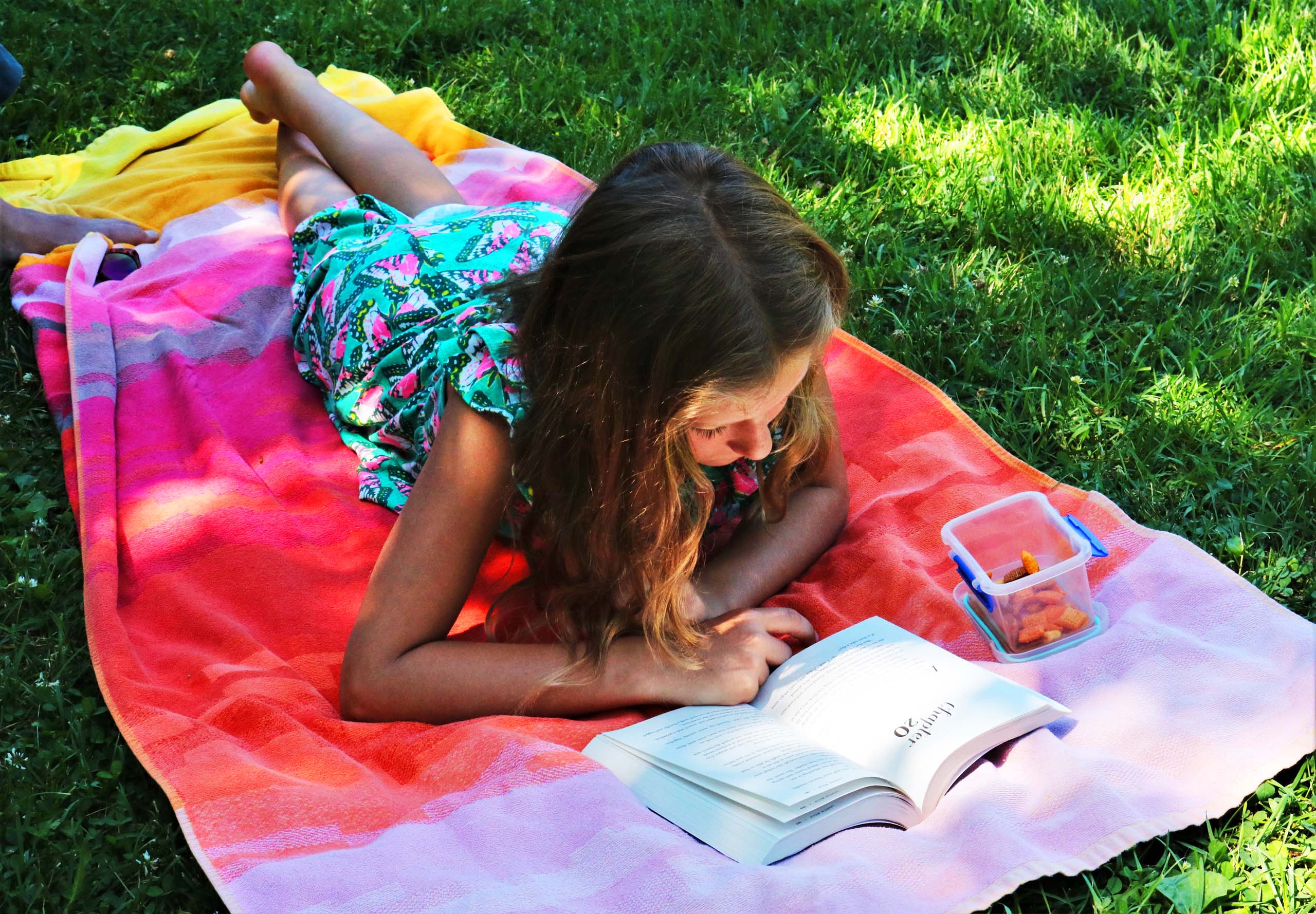 girl reading outside on a beach towel