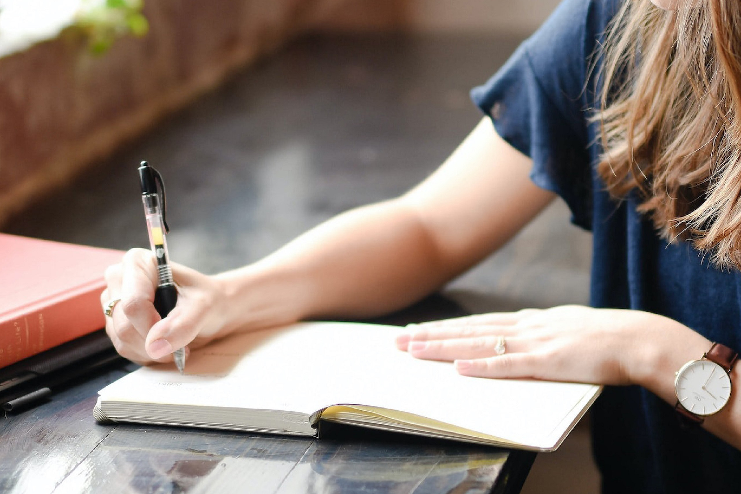 Close up of woman's hand writing with pen in journal