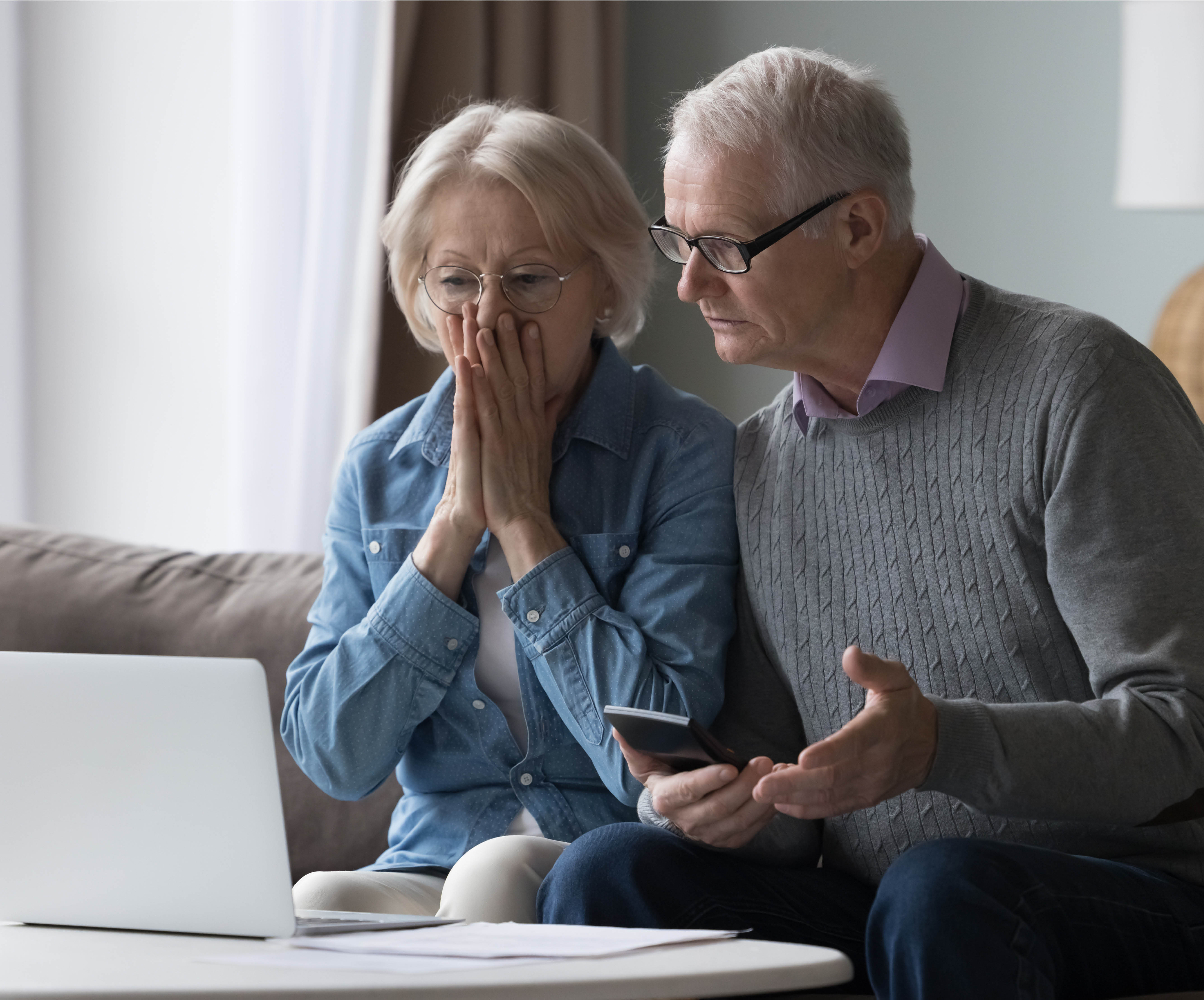 An elderly couple man and woman looking at an open laptop in concern