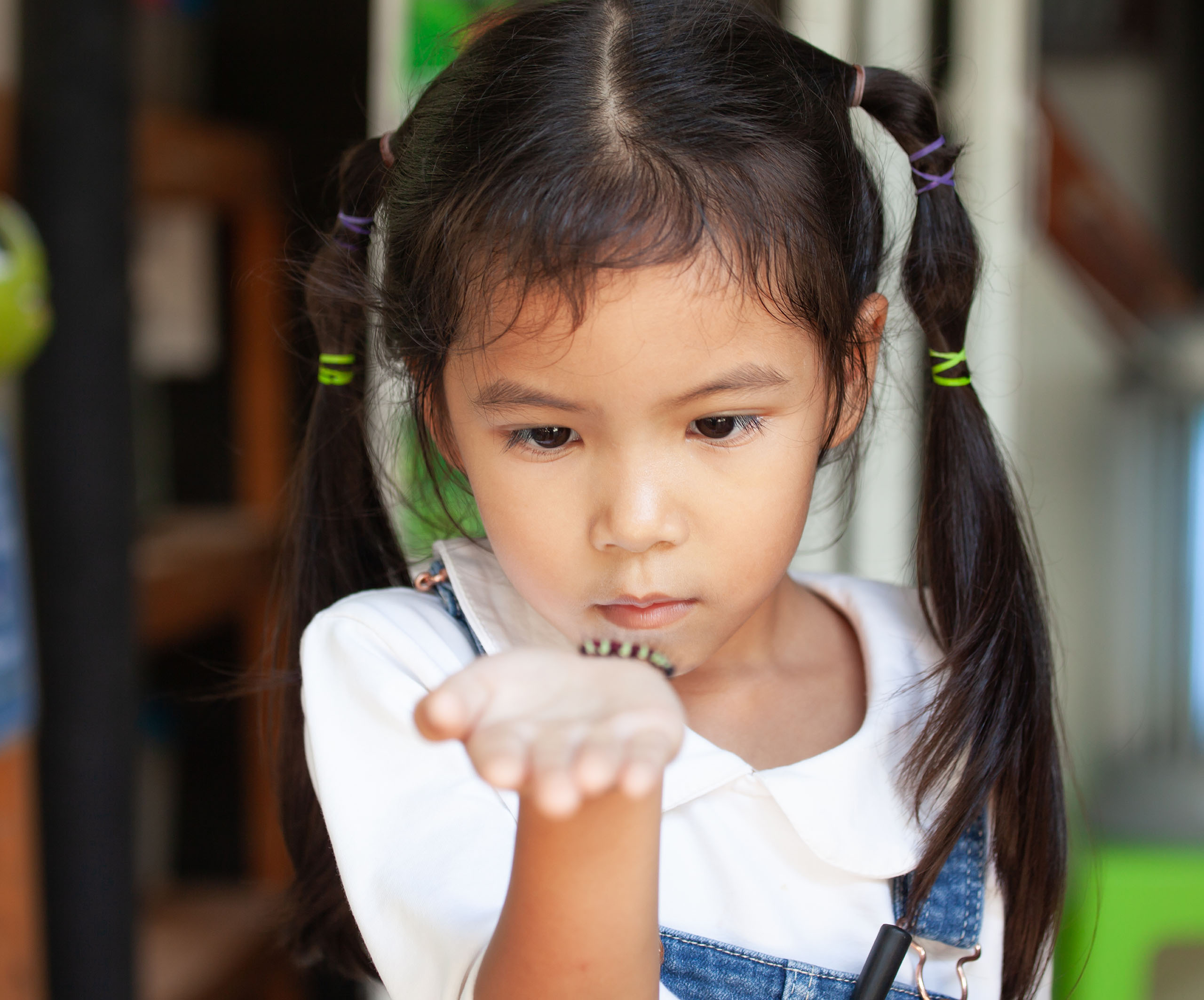 young girl holding caterpillar in hand