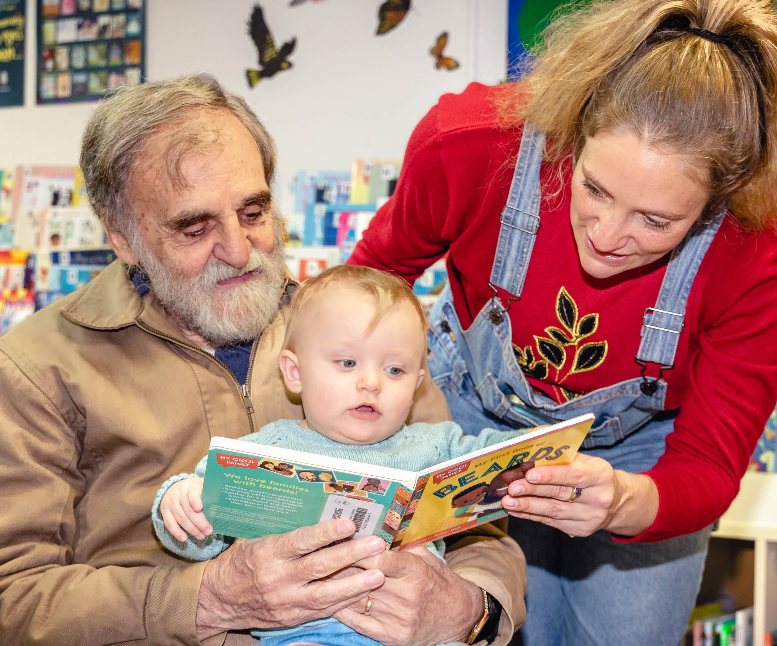 Grandfather mother baby boy reading Sylvania Library