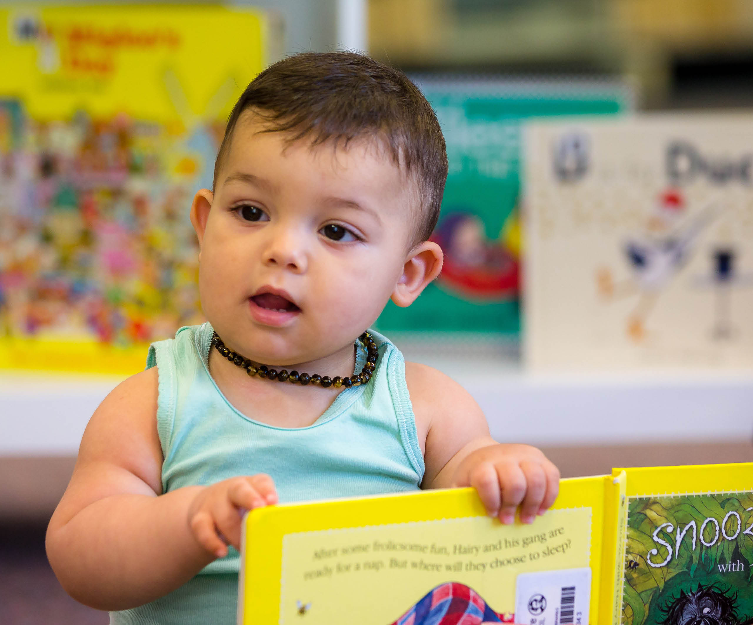 Brunette baby boy holding book Sutherland Library